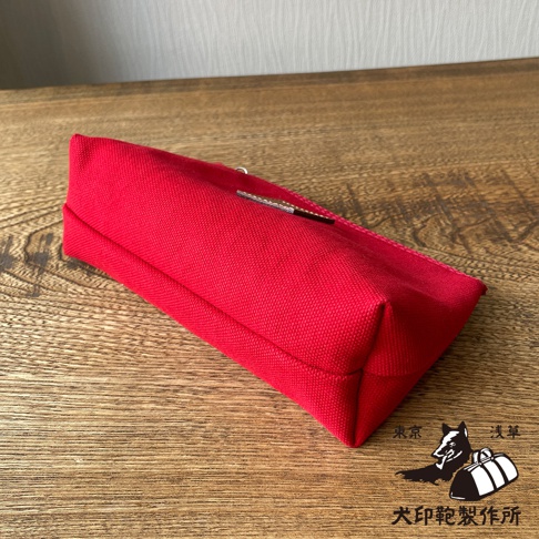 紅色石洗帆布小物收納包，小尺寸，材質為帆布，表面有細緻織紋，包體呈長方形，底部有縫線。