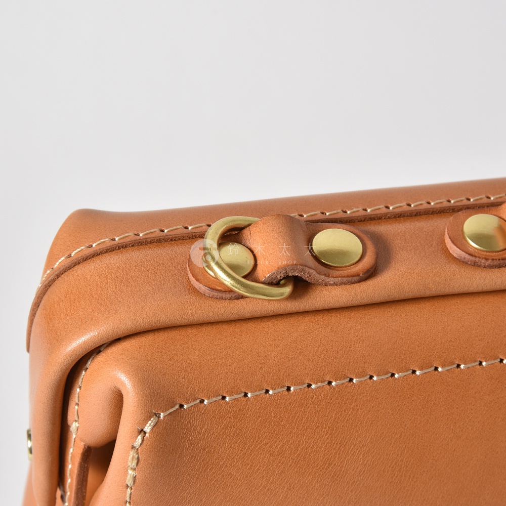 職人手作皮革軟式杜勒斯三用背包 BJ-16，特寫近拍，展示淺棕色皮革材質，帶有精緻縫線與復古黃銅五金配件，包含圓形掛環及圓形釦。