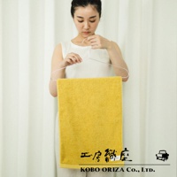 一名女子手持衣架，展示一條亮黃色的超細纖維毛巾，毛巾材質蓬鬆，具有高密度觸感。