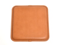 棕褐色皮革圓形坐墊，邊緣縫有白色車線，整體呈現簡約設計。