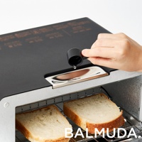 黑色蒸氣烤麵包機，頂部設有注水口，一隻手正用黑色量杯將水倒入。烤麵包機內有兩片烤吐司，放在銀色烤架上。