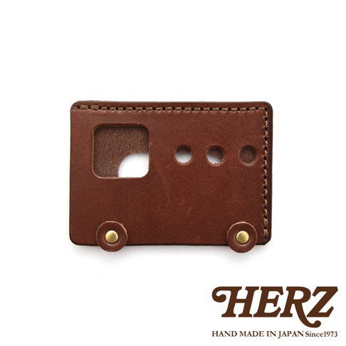 日本HERZ職人手作皮革交通卡收納夾，採用棕色皮革製成，造型像一輛小巴士，有圓形窗戶和車輪設計，底部印有HERZ品牌標誌和「HAND MADE IN JAPAN Since1973」字樣。