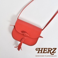 紅色皮革流蘇側背包，手工縫製，帶有壓紋扣環與流蘇裝飾，斜挎肩帶。