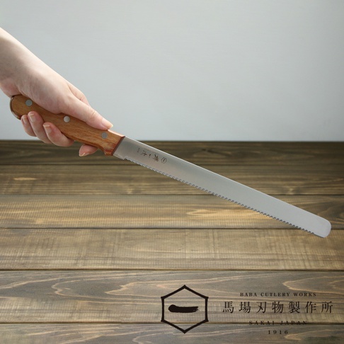 一只手握持著一把不鏽鋼鋸齒麵包刀，刀柄為木質，刀刃為銀色不鏽鋼。