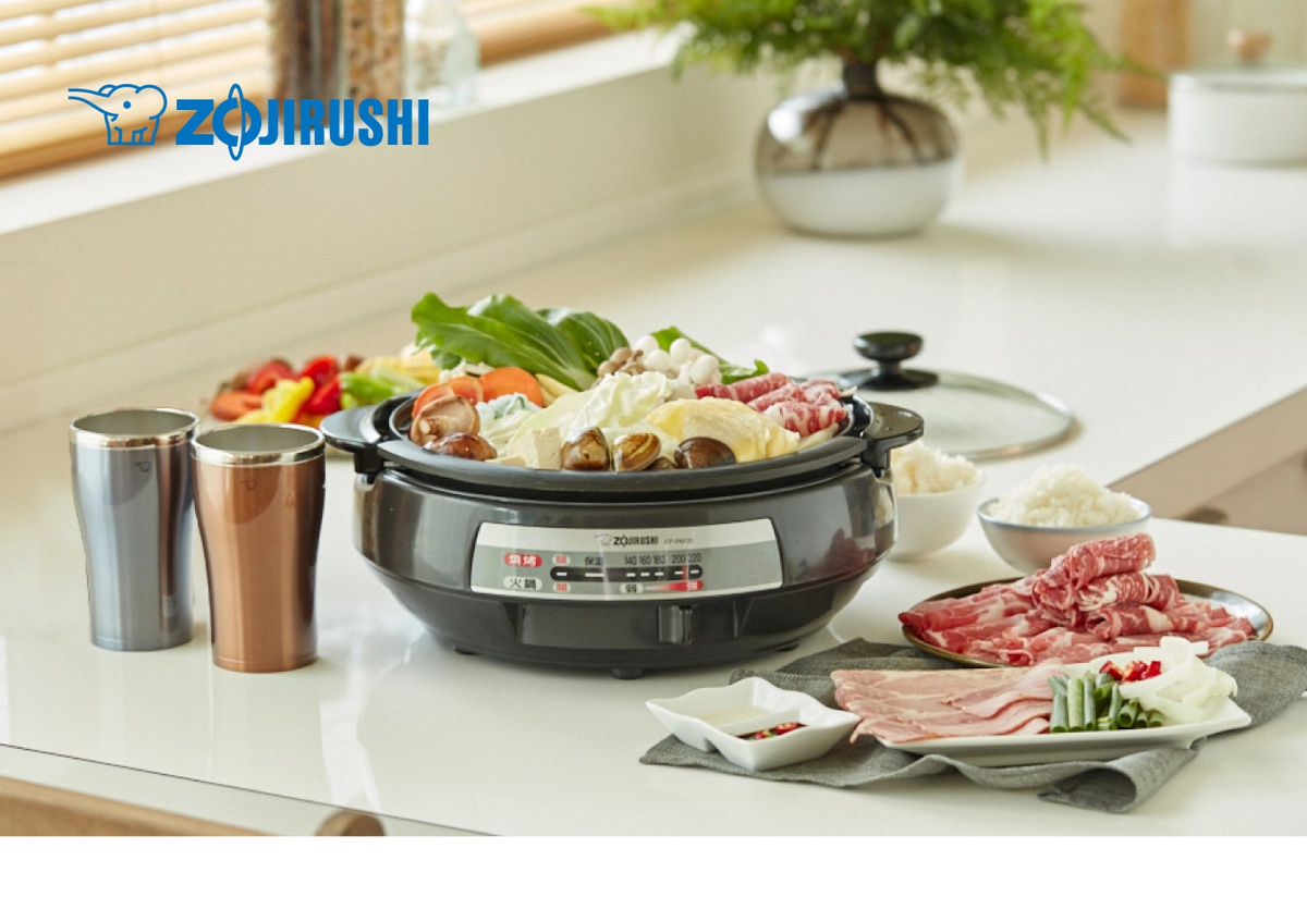 鐵灰色和銅色不鏽鋼杯，以及裝滿蔬菜、肉類和豆腐的黑色 Zojirushi EP-PAF25 萬用鍋。