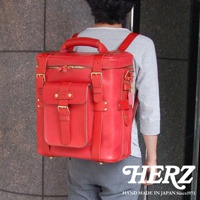 職人手作紅色皮革大型三用旅行後背包，配有黃銅扣環和拉鍊，正面有一個帶有皮帶和扣環的翻蓋口袋，側面有調節帶和掛飾，質感厚實。