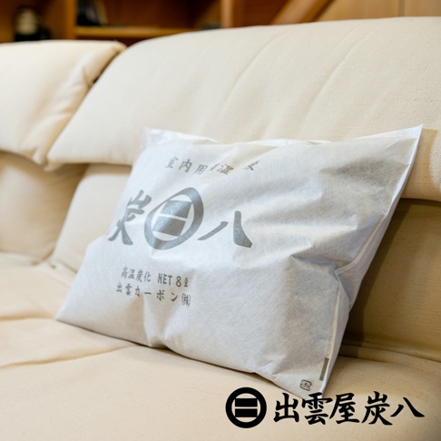 一個白色紙袋包裝的調濕木炭，上面印有灰色日文文字和品牌標誌。