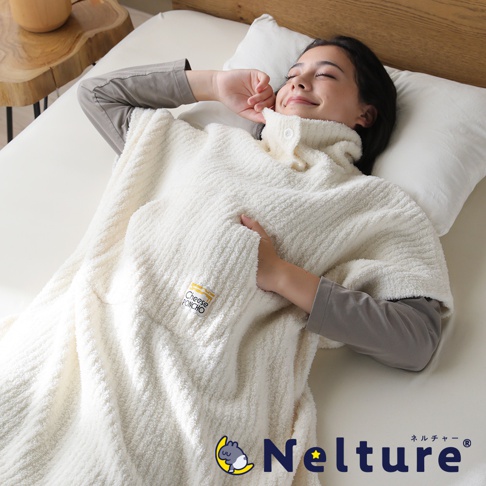 一位女士躺在床上，蓋著一件象牙白的起司斗篷，斗篷上有「CHEESE PONCHO」的標籤，斗篷下方為「Nelture」品牌標誌