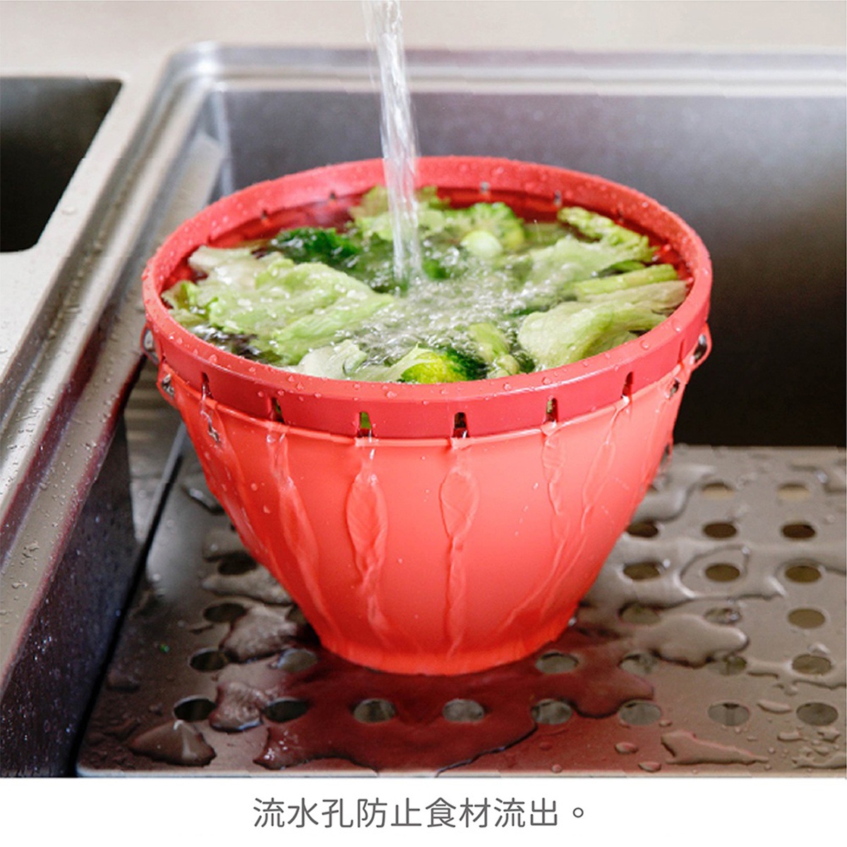 排水孔可防止食材流出，一個紅色的瀝水籃正在水槽中清洗蔬菜，水流從上方沖下。