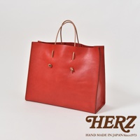 紅色皮革提袋，設有兩條皮革提把，正面有兩個皮革繫帶裝飾。