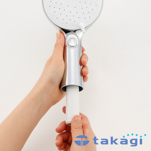 一雙手正在為 takagi KIREIST 真淨水水霧蓮蓬頭更換過濾濾芯，銀色質感的手持蓮蓬頭握把處設計可插入白色的長條形濾芯，畫面背景為純白，展示了安裝濾芯的過程。