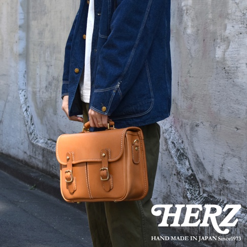 職人手作皮革商務休閒兩用單肩包，採用光滑棕褐色皮革製成，設有雙搭扣和頂部提把，搭配可拆卸肩帶。