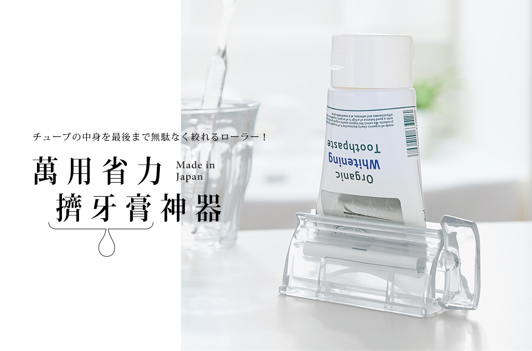 透明壓克力材質的手動轉轉擠牙膏夾，夾著一支白色印有藍色字樣的牙膏，產品結構簡潔，方便使用。