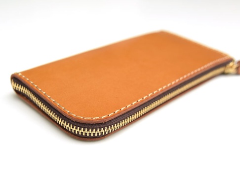 職人手作皮革L型拉鍊長夾，採用天然棕色皮革，搭配金色拉鍊與米白色縫線，呈現簡約質感。