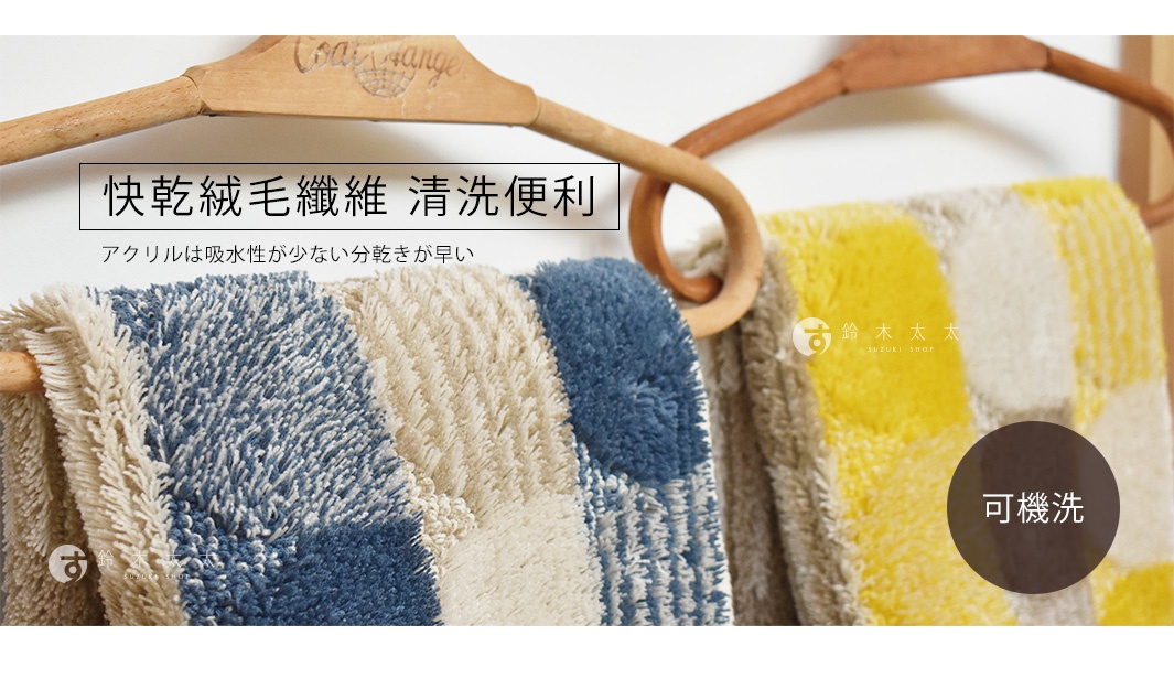 兩條毛絨地墊，一條為藍色與米白色方塊格紋，另一條為黃色與米白色方塊格紋，皆為長纖維材質，掛在木質衣架上。