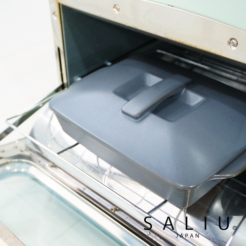 灰色耐熱陶製萬用長方形烤盤，帶有同色系手柄蓋，放置於烤箱架上。