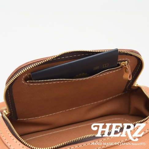 HERZ 職人手作皮革拉鍊旅行斜背包 F-7 內部特寫，展現皮革的質感與精緻縫線，內袋有一個放護照的隔層。