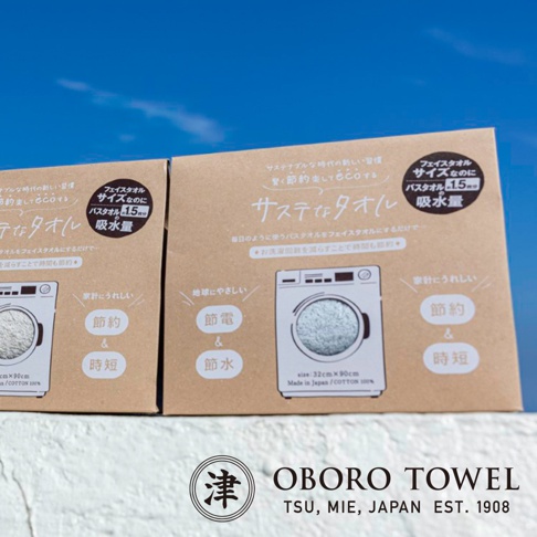 兩件式卡其色環保永續毛巾包裝盒，上面印有日文說明與洗衣機圖示，強調節電節水與尺寸規格。