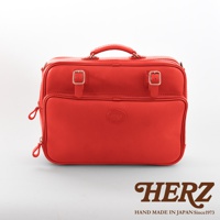 鮮紅色皮革製作的兩用商務公事包，正面有兩個金屬釦帶和拉鍊隔層，上方有提把，側邊有可拆卸的肩帶。