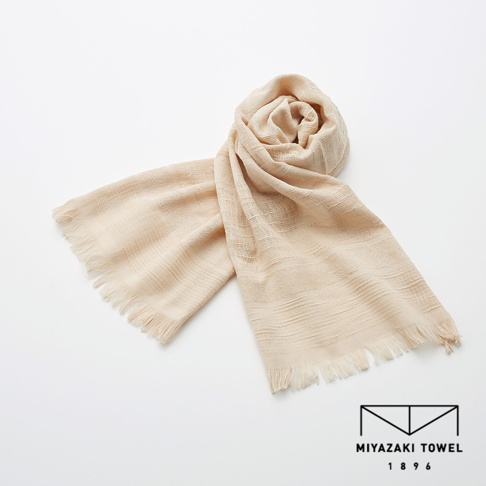 今治匹馬棉圍巾，淺米色，質地輕柔，帶有流蘇邊緣，織紋細膩，展現日式簡約風格。