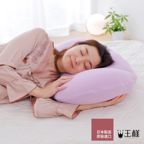 一位女子側臥，頭枕在薰衣草色枕套的舒肩枕上，枕頭形狀符合人體工學，提供頸部和肩部支撐。