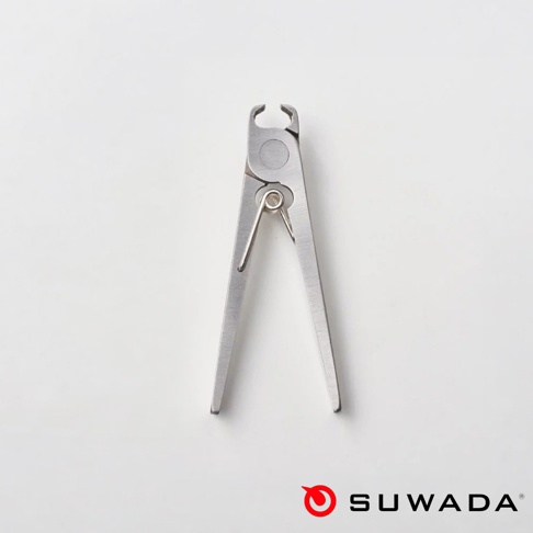 白色背景上放置一把日本諏訪田製作所 SUWADA 的金屬指甲剪，設計簡約精緻，金屬表面呈現細膩的銀灰色光澤，右下角配有紅色的圓形商標與黑色的 SUWADA 文字。