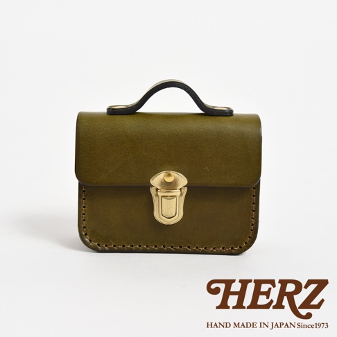 橄欖綠皮革迷你收納包，配有金色鎖扣和黑色皮革提把，手工縫製。