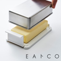 日製奶油盒，包含一塊黃色奶油和一個有白色提把的淺灰色底座，上方蓋著一個銀色金屬蓋。