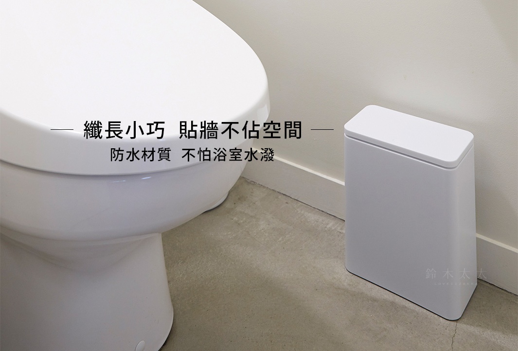 白色簡約長方形垃圾桶，有按壓式掀蓋，置於浴室角落，旁邊是白色馬桶。
