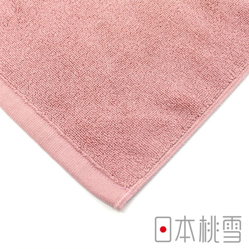粉紅色絨毛浴墊，材質柔軟，邊緣有精緻縫線，角落印有「日本桃雪」標誌。