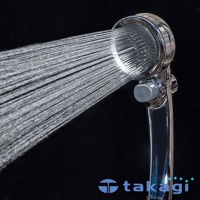 銀色金屬材質蓮蓬頭，正在噴射細緻水流，側面有灰色調節按鈕。