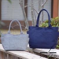 兩款三河木綿刺子織手提托特包，一款為白色底黑格紋，另一款為深藍色。兩款皆為 L 尺寸，採用經典托特包款式，有雙提把，包身呈現樸實的織紋質感，外側設有方便收納的口袋。