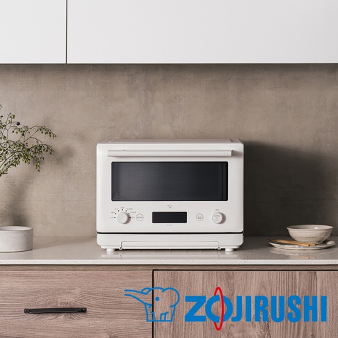 白色烤箱式微波爐，配備黑色玻璃門和銀色控制旋鈕，置於淺色檯面，背景為灰色紋理牆面。