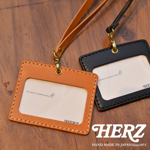 職人手作皮革橫式證件識別夾，展示棕色和黑色兩款。兩款證件夾均為皮革材質，帶有透明卡片視窗，並配有金屬掛鉤和皮革掛繩。