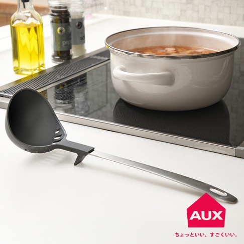 AUX leye 不沾桌多用濾水湯匙，銀色金屬手柄，灰色湯勺頭，上面有圓孔，湯勺放在有白色湯鍋的電磁爐上