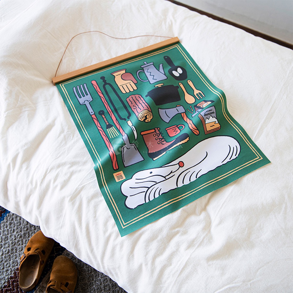 綠色帆布藝術海報，以木條懸掛，描繪了多種冬季戶外活動相關的插畫，包含鍋具、手套、柴火、斧頭、靴子、水壺及一隻趴臥的白色動物。