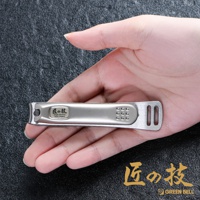 手握銀色不鏽鋼曲刃指甲剪，上面有日文「匠の技」和英文「High Quality Nail clipper」標誌，以及9個小圓點和兩個長方形孔的防滑設計。