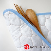 一張白色兩層蚊帳棉織吸水墊，帶有藍色滾邊，墊內有木質湯匙和三支木筷。