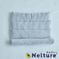 淺藍色毛巾材質的Nelture捲捲快眠今治毛巾枕，表面有四道縫線，一端捲起，放置於淺色紋理布料上。