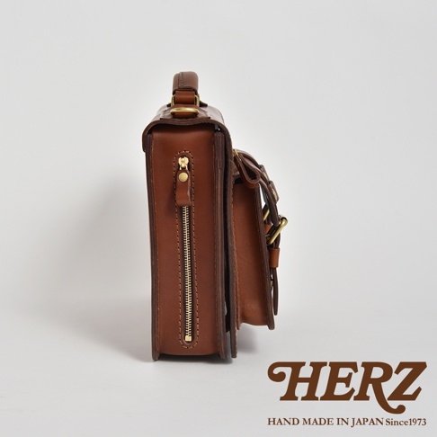 職人手作皮革雙口袋兩用單肩包 A-19，側邊視角，呈現棕色皮革材質，搭配金色拉鍊和金屬扣環，包款造型簡潔。
