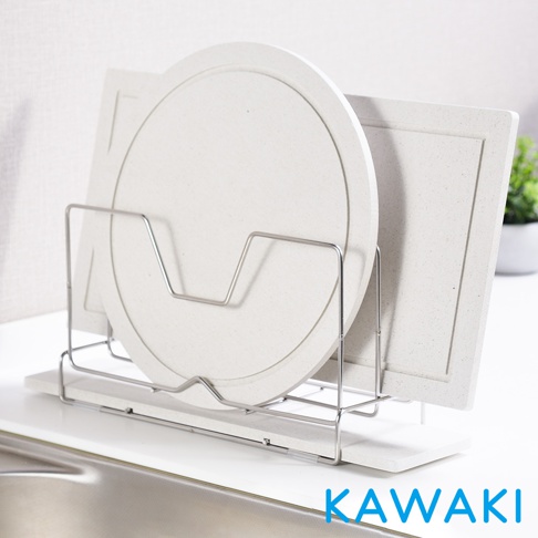 金屬架上置放兩個淺色珪藻土鍋蓋和砧板，左邊為圓形鍋蓋，右邊為方形砧板，架子下方為淺色珪藻土底座，整體呈簡約風格。