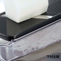 四合一刨絲器，黑色刨絲板，搭配透明儲物盒，內裝刨好的白蘿蔔絲。