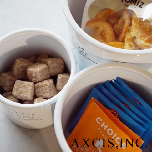 三個白色琺瑯儲物罐，分別裝有紅糖方塊、乾果片和藍色包裝的茶包。