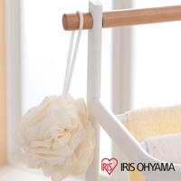 白色金屬框架的毛巾架，搭配原木橫桿，懸掛著一個米白色網狀沐浴球，下方掛有黃色和白色毛巾。