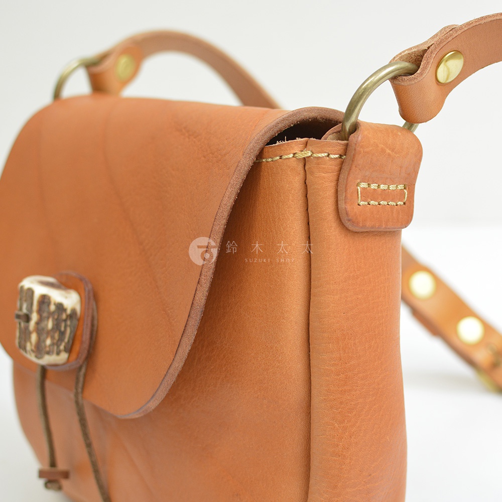 職人手作皮革鹿角扣繩肩背包，採用淺棕色皮革，附有鹿角狀的扣環和銅質金屬配件。