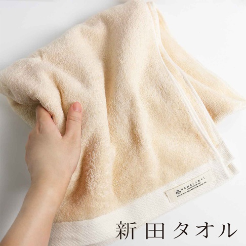 淺米色無漿有機棉柔浴巾，質地蓬鬆，一角有品牌標籤，標示「namatowel ORGANIC COTTON 100% MADE IN JAPAN」。