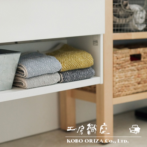 淺灰色、灰色及黃色毛巾，疊放在白色層架上，部分可見紋理。