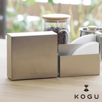 日製 KOGU 珈琲考具分隔式不鏽鋼咖啡濾紙收納盒，搭配玻璃咖啡豆儲存罐與金屬手沖咖啡壺，置於木質桌面。