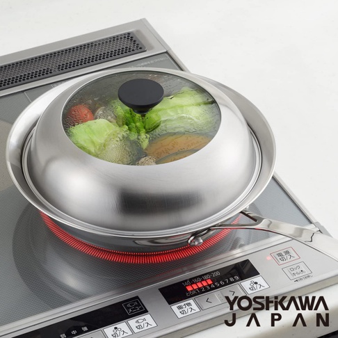 不鏽鋼蒸鍋盤，配有透明玻璃蓋，盤內盛有蒸煮的蔬菜，如白菜、番茄和胡蘿蔔。蒸鍋盤放置於電磁爐上，鍋底有紅色加熱指示。