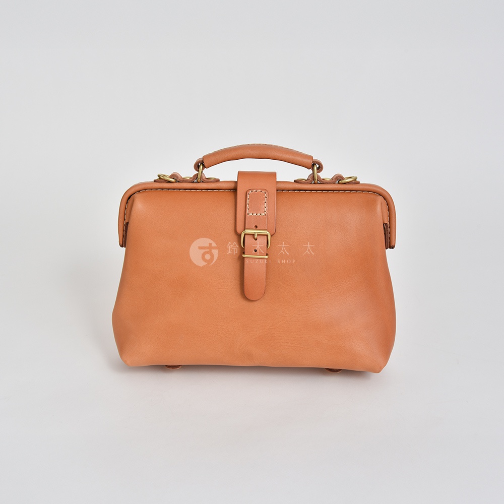 職人手作皮革迷你軟皮杜勒斯包，淺棕色，帶有黃銅釦帶和提把，整體風格復古。